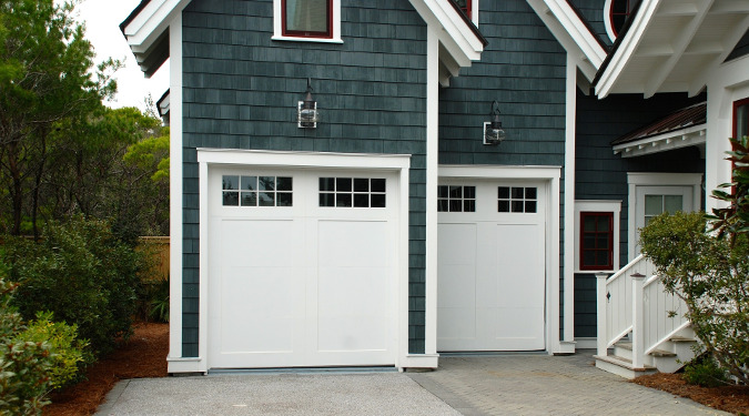 Cristina Moss Naturals started from a garage. A picture of a garage with a white garage door and blue wood shingles on the exterior.